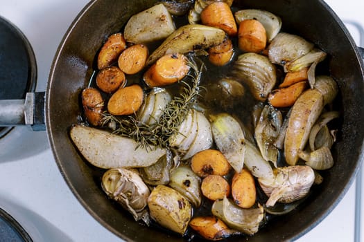 Chopped vegetables with spices are stewed in a frying pan on the stove. Top view. High quality photo