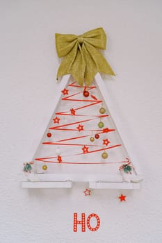 Figurine in the shape of a decorated Christmas tree on a white wall. High quality photo