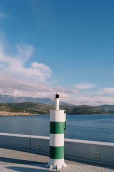 Navigation beacon on the pier against the backdrop of mountains. High quality photo