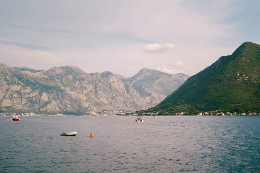 Boats float in the bay against the backdrop of a green mountain range. High quality photo