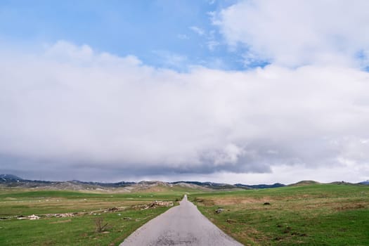 Asphalt road on green plain to high mountain ridge. High quality photo