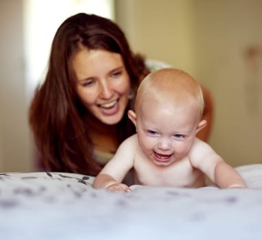 Laughing, playing and a mother with a baby on the bed for bonding, love and care in the morning. Wake up, smile and a mom with a kid or family together in the bedroom of a house for happiness.