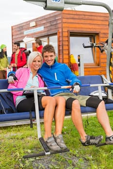 Smiling hugging couple sitting and waiting on chair-lift