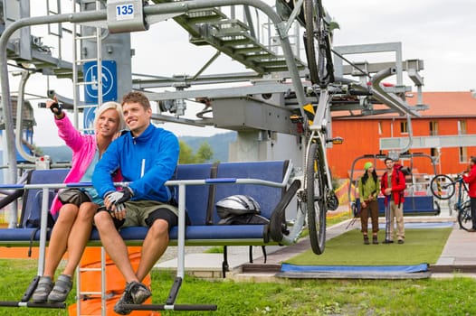 Happy couple traveling by chair lift enjoying landscape