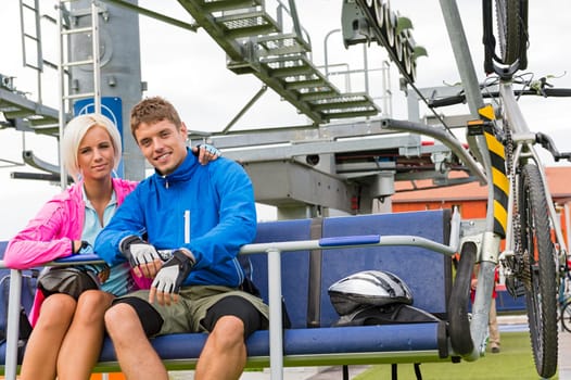 Young couple sitting on chair lift waiting for departing