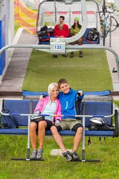 Cuddling couple pointing on chair lift in sweatsuits