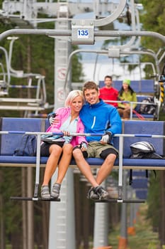 Cuddling young couple sitting on chair lift in the pinewood