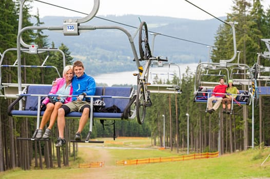 Smiling couples using chair lift in scenic landscape