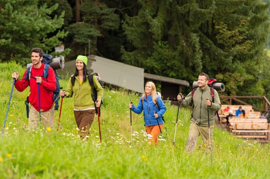 Smiling young people trekking in nature landscape with sticks