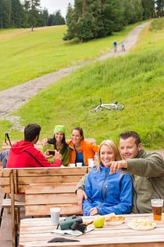 Young sporty tourists resting on wooden bench nature pointing direction