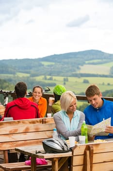 Smiling young couple resting looking at map sitting mountain countryside