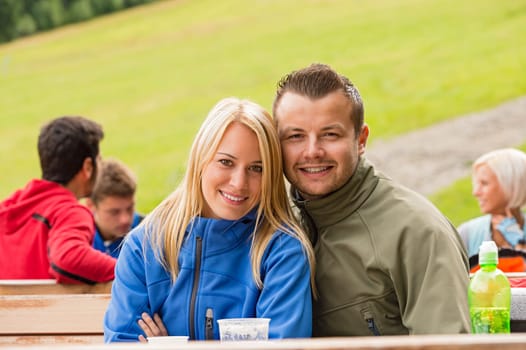 Smiling couple sitting and looking at camera outdoors weekend