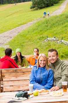 Young sporty tourists drinking refreshments and resting on wooden bench