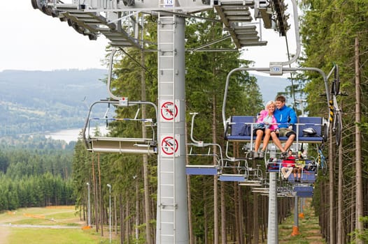 Cuddling couple going through pinewood by chair lift