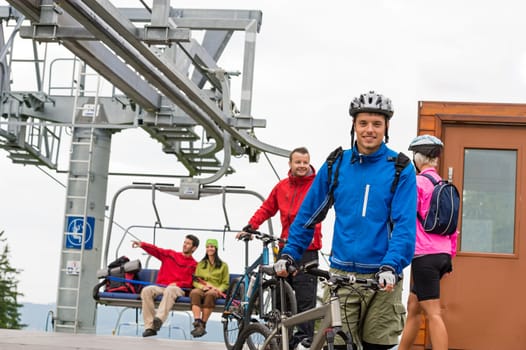 Sporty couple getting on bicycles after chair lift trip
