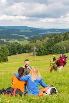 Young hiking friends resting and taking photograph in scenic view