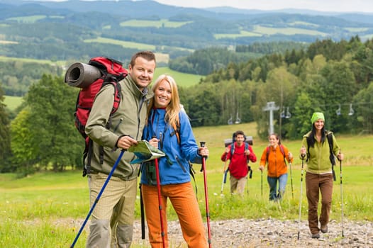 Smiling couple posing with hiking sticks and map on track