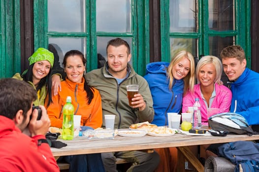 Young man taking picture of smiling friends during weekend