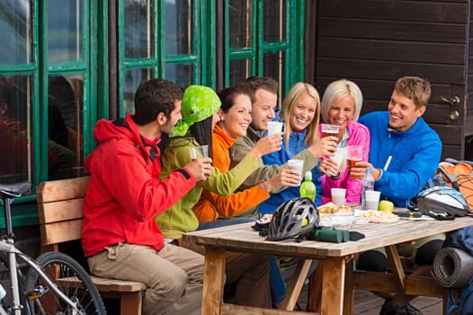 Happy young people resting and drinking beer after biking