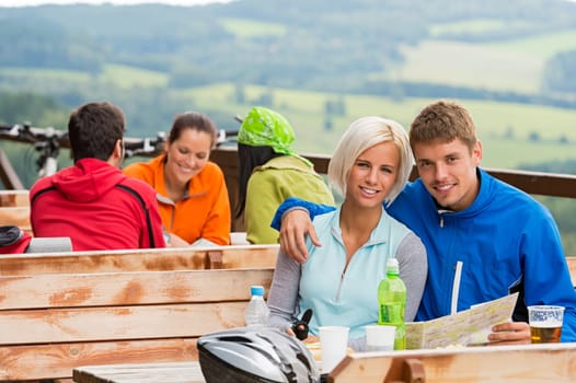 Cuddling couple reading map with scenic view at background