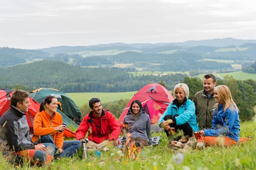 Smiling young people enjoying nature beside tents and scenic view