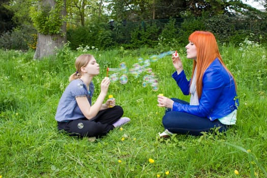 Little girl and young woman blowing soap bubbles