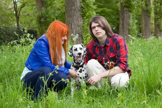 Young couple with a dog on the grass in the park