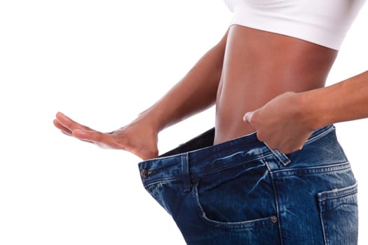 Young african woman in old jeans pant after losing weight. Isolated on white background.