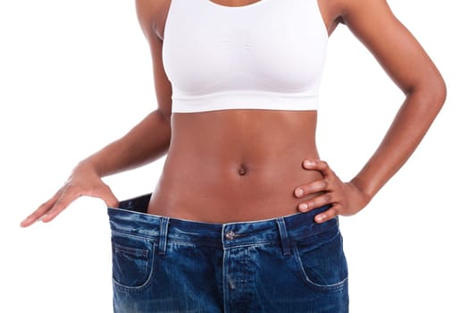 Young african woman in old jeans pant after losing weight. Isolated on white background.