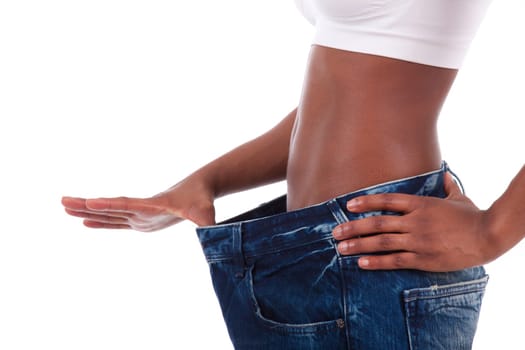 Young african woman in old jeans pant after losing weight. Isolated on white background.