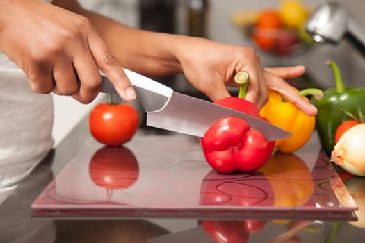 African  American womans hand slicing a red pepper