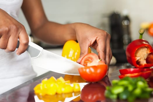 African  American womans hand slicing a tomatoe