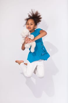 Portrait of cute Young African American girl jumping, over gray background