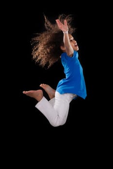 Portrait of cute Young African American girl jumping, over black background