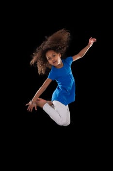 Portrait of cute Young African American girl jumping, over black background