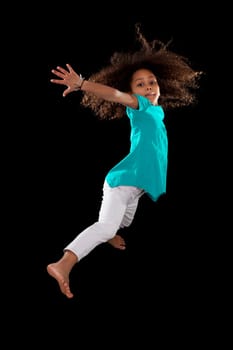 Portrait of cute Young African American girl jumping, over black background