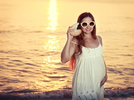Beautiful pregnant woman at sunrise near the sea