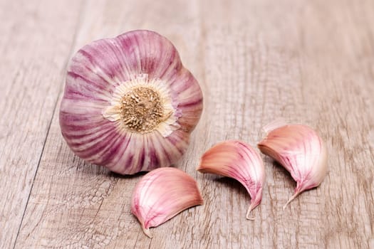 Garlic with three cloves of garlic on an old wooden board