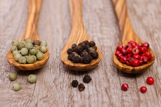 Green,black and red pepper on a wooden spoon