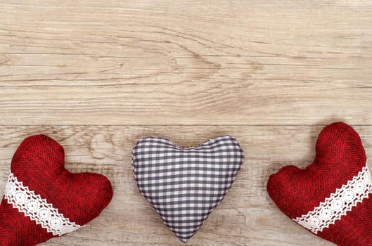 Old board with three hearts made of fabric and copy space