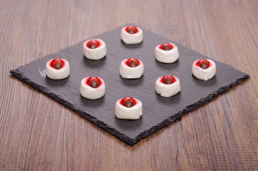 Nine small goat cream cheese with frosting ladybugs