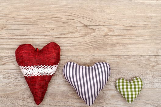 Weathered wooden board and three hearts made of fabric