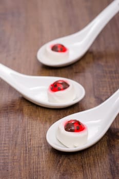 Goat cheese with frosting ladybug on porcelain spoon
