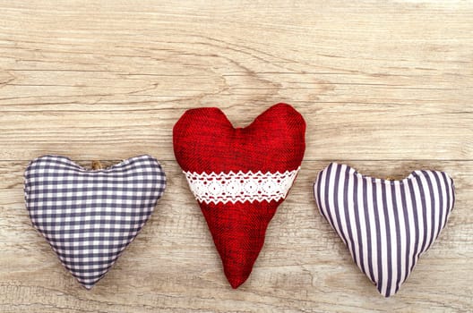 Three fabric hearts on an old wooden board