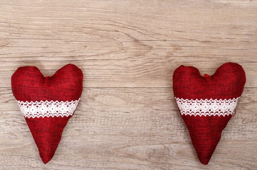 Two red hearts made of fabric with border on a weathered wood