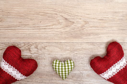 Text space for congratulations on a wooden board with three hearts made of fabric