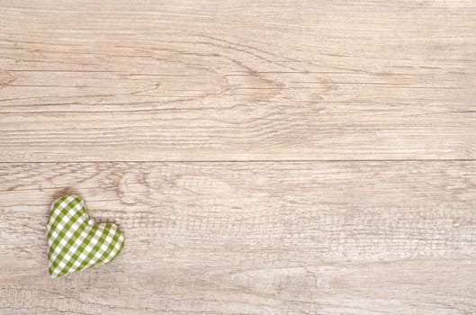 Green checkered heart made of handmade fabric on weathered wooden board