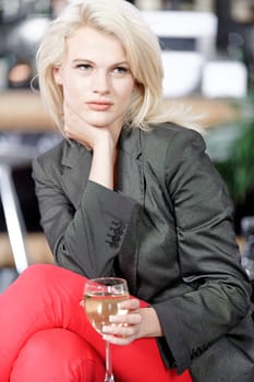 Attractive young woman enjoying a glass of white wine in a wine bar.