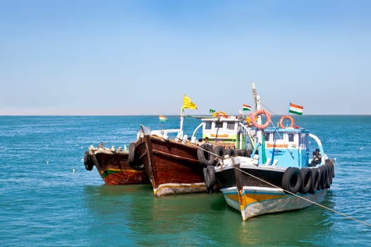 Horizontal seascape of Indian passenger ferries moored under a blue sky of the shoreline at Bet Dwarka, Gujarat, India
