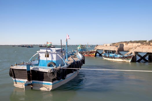 Horizontal capture of fishing boats moored at the pier of the holy hindu island of Bet Dwarka late afternoon late afternoon shot in Gujarat India under blue skies